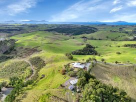 A rural landscape with green rolling hills a house a road and distant coastline at Glenmohr Cabin  Waipu Holiday Retreat in Waipu