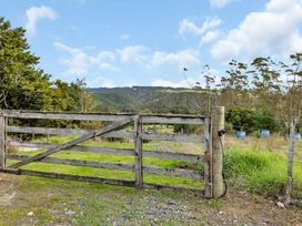 A wooden farm gate with wire fencing and green grass with hills and trees in the background at Glenmohr Cabin - Waipu Holiday Retreat in Waipu