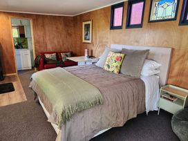 A bedroom with a bed and a couch at Tui Cottage - Waipu Holiday Retreat Waipu