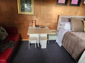 A bedroom with a bed, table, and seating area at Tui Cottage - Waipu Holiday Retreat, Waipu