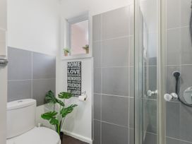 A bathroom with a toilet plant a window and a glass shower at Picton Central - Picton Holiday Home in Picton