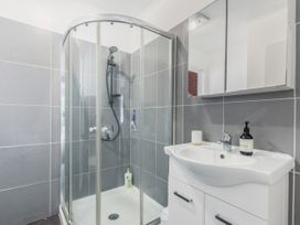 A bathroom with a corner glass shower enclosure and a white sink cabinet with a mirror at Picton Central - Picton Holiday Home in Picton