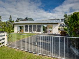 A single story house with a driveway and metal gate in front at Mahia Bliss - Surf & Serenity Holiday Home Mahia Peninsula