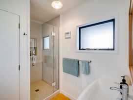 A bathroom with a glass shower enclosure a window towels hanging on a rail and a sink with a faucet at Mahia Bliss - Surf & Serenity Holiday Home in Mahia Peninsula