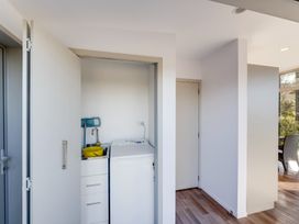 A laundry area with a washing machine a sink and cleaning tools at Mahanga Dunes Retreat - Mahia Holiday Home in Mahia Peninsula