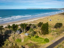 A coastal landscape with a sandy beach a road trees and small buildings at Mahanga Dunes Retreat - Mahia Holiday Home Mahia Peninsula