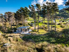A single story house surrounded by trees and grass on a hillside at Mahanga Dunes Retreat - Mahia Holiday Home in Mahia Peninsula