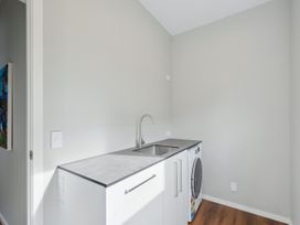 A laundry room with a sink and washing machine at Seabreeze Retreat - Paraparaumu Beach