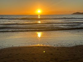 A sunset over the ocean with gentle waves at Seabreeze Retreat - Paraparaumu Beach