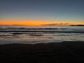 A beach with a sunset over the ocean at Seabreeze Retreat - Paraparaumu Beach