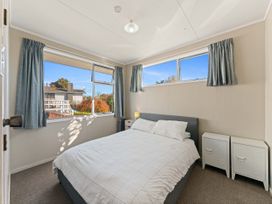 A bedroom with a bed and windows at The Bay Breeze Retreat - Two Mile Bay