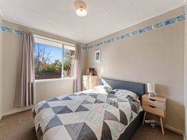 A bedroom with a bed and nightstand at The Bay Breeze Retreat - Two Mile Bay