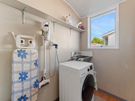 A laundry room with a washing machine and ironing board at The Bay Breeze Retreat - Two Mile Bay