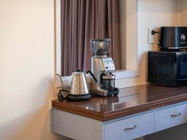 A kitchen counter with a coffee grinder, coffee maker, and kettle at The Bay Breeze Retreat - Two Mile Bay