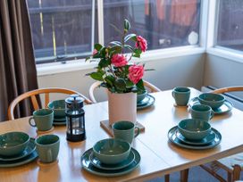 A dining room table set with dishes and a flower arrangement at The Bay Breeze Retreat - Two Mile Bay
