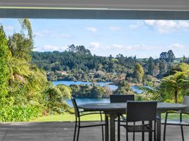 A patio with a table and chairs overlooking a lake and trees at Okere Jetty Escape Rotoiti Holiday Home in Okere Falls