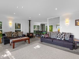A living room with two sofas, a wooden coffee table, a wood-burning stove, and a dining area at Okere Jetty Escape -  Rotoiti Holiday Home in Okere Falls