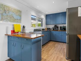 A kitchen with blue cabinets wooden countertops refrigerator stove and kitchen appliances at Okere Jetty Escape  Rotoiti Holiday Home in Okere Falls