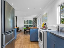 A kitchen with blue cabinets a white stove a stainless steel refrigerator and a dining table with chairs at Okere Jetty Escape in Okere Falls