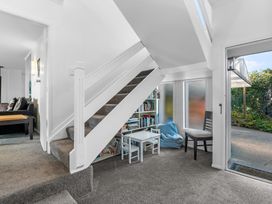 A carpeted stairway with a children's table and chairs underneath next to a bookshelf and a chair near an entrance at Okere Jetty Escape  Rotoiti Holiday Home in Okere Falls