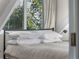 A bedroom with a bed and four pillows next to a window with curtains at Okere Jetty Escape Rotoiti Holiday Home in Okere Falls