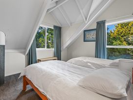 A bedroom with two single beds wooden bench under windows and blue curtains at Okere Jetty Escape  Rotoiti Holiday Home in Okere Falls
