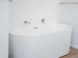A white freestanding bathtub with a wall-mounted faucet in a bathroom at Okere Jetty Escape in Okere Falls