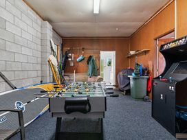 A game room with a foosball table arcade machine paddle boards and a sofa at Okere Jetty Escape - Rotoiti Holiday Home in Okere Falls