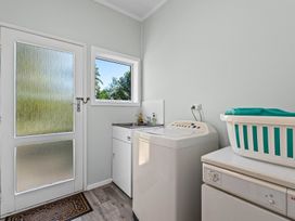 A laundry room with a washing machine sink and laundry basket at Okere Jetty Escape Rotoiti Holiday Home in Okere Falls