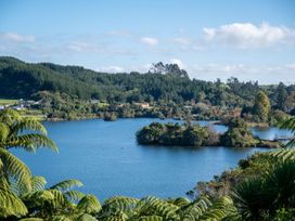 A lake with small islands surrounded by trees and houses in a forested area at Okere Jetty Escape  Rotoiti Holiday Home Okere Falls