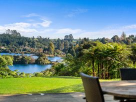 A view of trees and a lake with a wooden table and chairs in the foreground at Okere Jetty Escape Rotoiti Holiday Home in Okere Falls