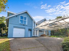 A blue two-story house with a garage and a covered carport at Okere Jetty Escape in Okere Falls