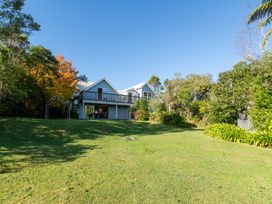A house with a large grassy yard and trees surrounding it at Okere Jetty Escape Rotoiti Holiday Home in Okere Falls