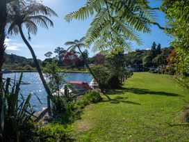A riverside with boats docked near grass and trees at Okere Jetty Escape  Rotoiti Holiday Home in Okere Falls