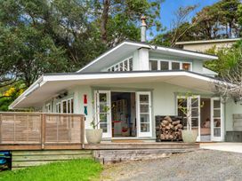 A house with open double doors a wooden deck and stacked firewood at Heron's Hideaway - Snells Beach Holiday Home in Snells Beach
