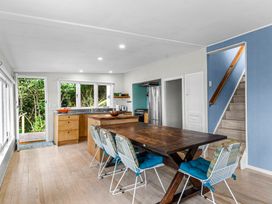 A kitchen and dining area with a wooden table and chairs next to stairs at Heron's Hideaway - Snells Beach Holiday Home in Snells Beach