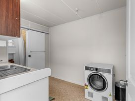 A laundry room with a washing machine a sink and a sliding door at Heron's Hideaway - Snells Beach Holiday Home in Snells Beach
