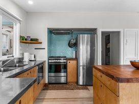 A kitchen with wooden cabinets stainless steel appliances a wooden island and blue tile backsplash at Heron's Hideaway - Snells Beach Holiday Home in Snells Beach