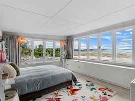 A bedroom with large windows showing a water view and next to a garden at Heron's Hideaway - Snells Beach Holiday Home in Snells Beach