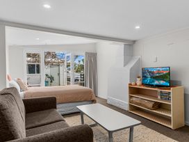 A room with a couch a coffee table a bed and a TV on a wooden shelf at Heron's Hideaway - Snells Beach Holiday Home in Snells Beach