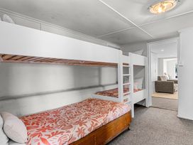A bedroom with bunk beds and a single bed with patterned bedding at Heron's Hideaway - Snells Beach Holiday Home in Snells Beach