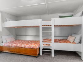 A bedroom with white bunk beds and orange patterned bedding at Heron's Hideaway - Snells Beach Holiday Home in Snells Beach