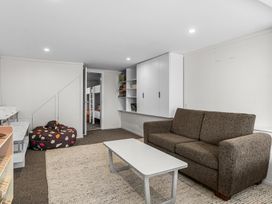 A living area with a brown sofa a white coffee table and white cabinets on the wall at Heron's Hideaway - Snells Beach Holiday Home in Snells Beach