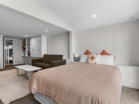 A bedroom with a bed and pillows a sofa and a coffee table near a shelving unit at Heron's Hideaway - Snells Beach Holiday Home in Snells Beach