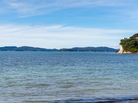 A beach view with water and mountains at Heron's Hideaway - Snells Beach