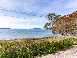 A view of the ocean and beach with greenery at Heron's Hideaway - Snells Beach