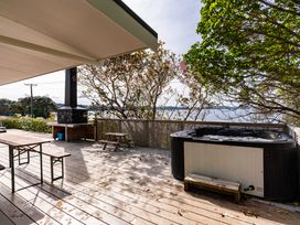 An outdoor deck with a hot tub and table at Heron's Hideaway - Snells Beach