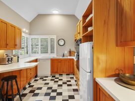 A kitchen with wooden cabinets a refrigerator dishwasher a wall clock and checkered floor at Stylish Fendalton Townhouse - Prime Location Christchurch