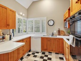 A kitchen with wooden cabinets white countertops a stainless steel sink dishwasher and checkered floor at Stylish Fendalton Townhouse Prime Location Christchurch