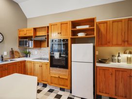 A kitchen with wooden cabinets a white refrigerator a black oven a microwave and a checkered floor at Stylish Fendalton Townhouse - Prime Location Christchurch